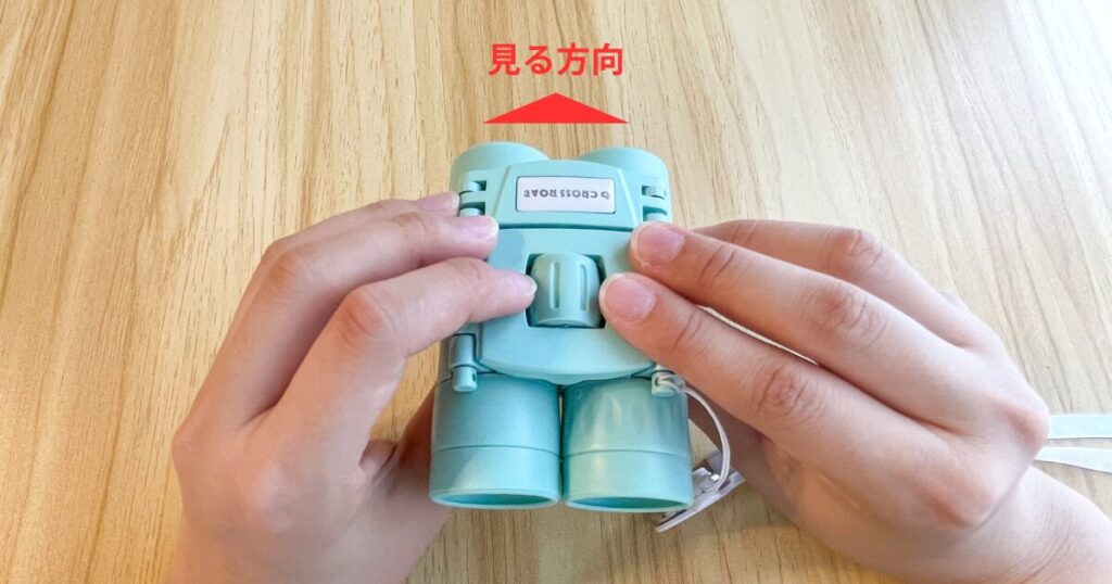 双眼鏡を上から見た写真、見る方向を赤矢印で示す