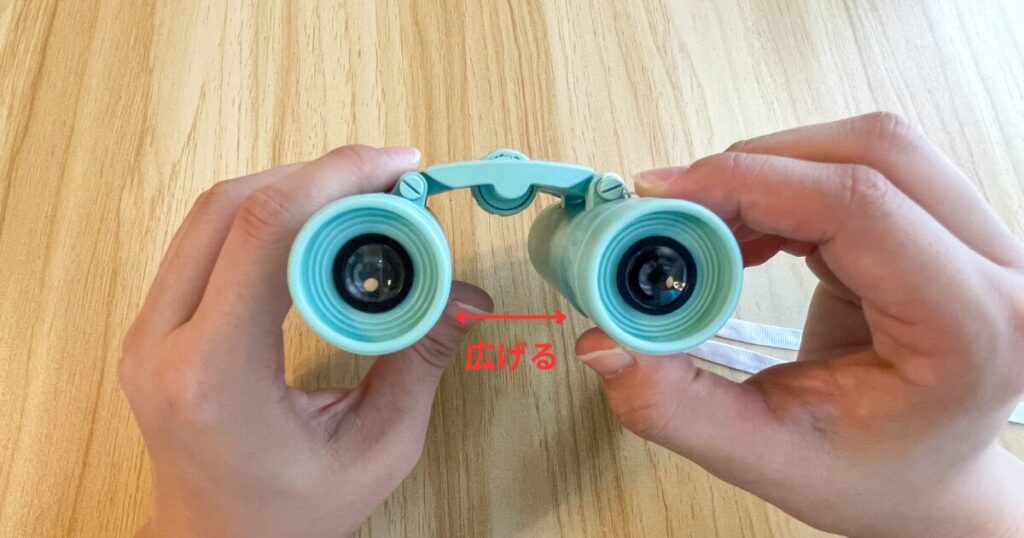 両手で双眼鏡を持って、目幅に広げた写真