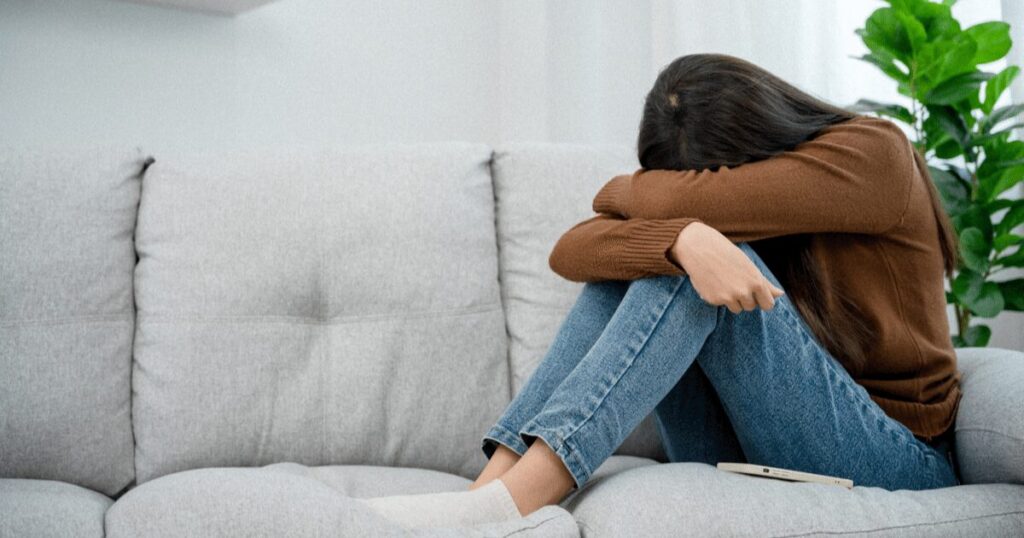 女性が一人で頭を抱えて座っている写真