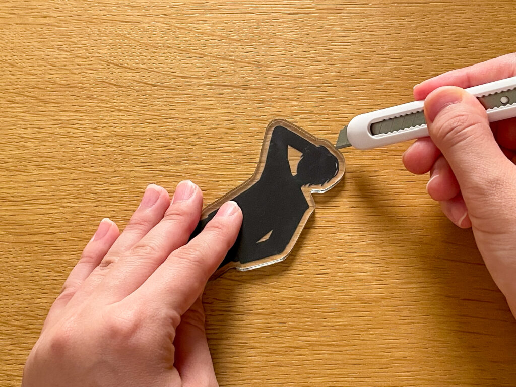 自作アクスタにカッターの刃を当てている様子